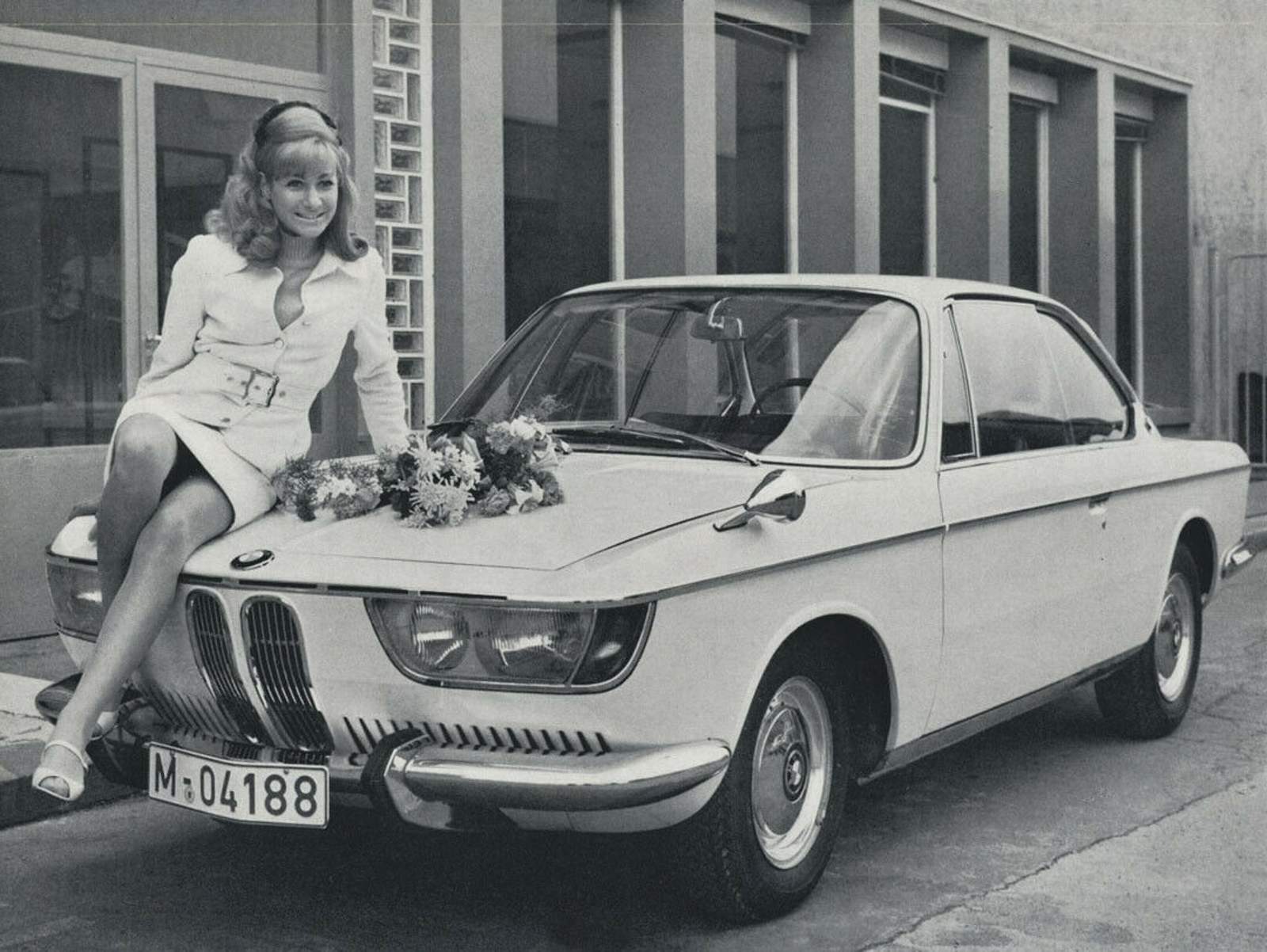BMW 2000 CS - Fotografía promocional de época con modelo sobre el capó adornado de flores